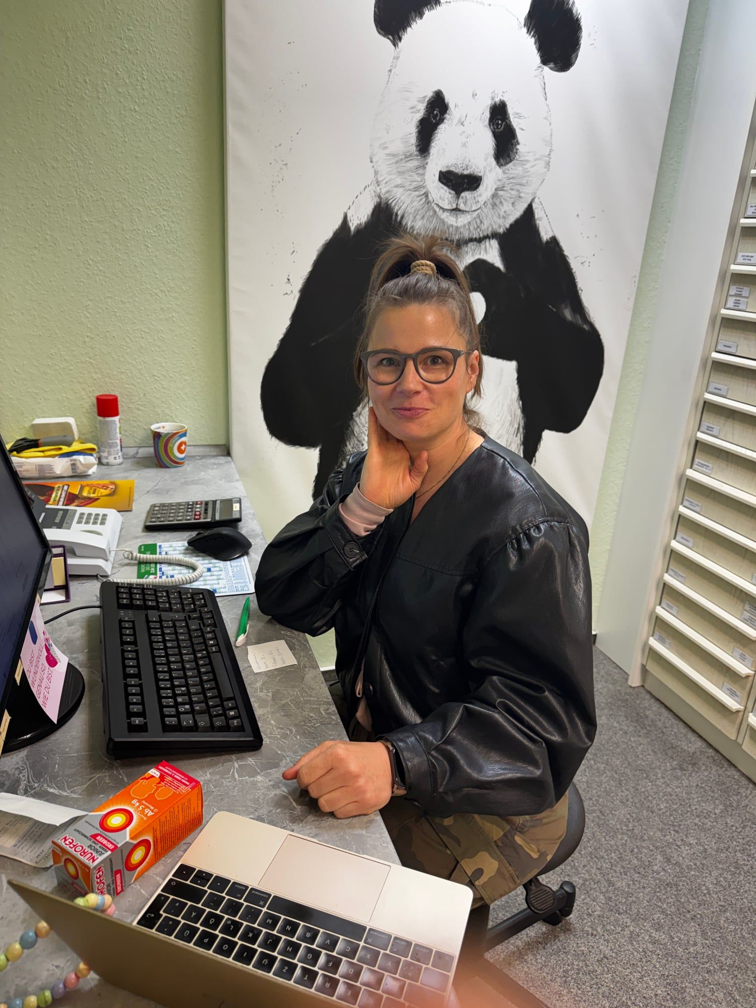 Kollegin am Schreibtisch vor dem Panda-Wandbild